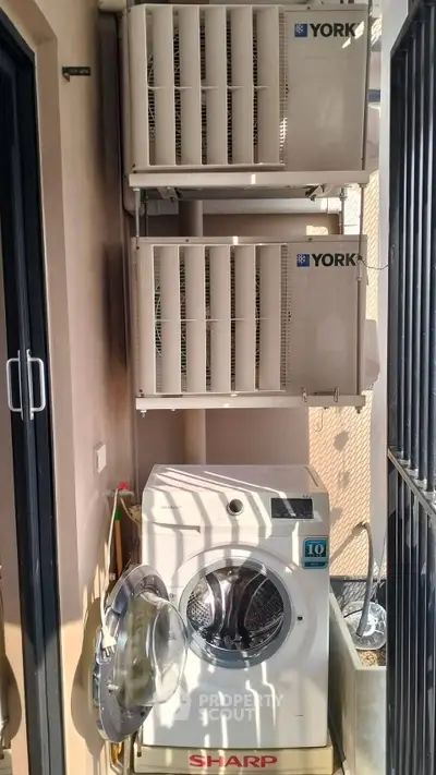 Compact outdoor laundry area with washing machine and air conditioning units.