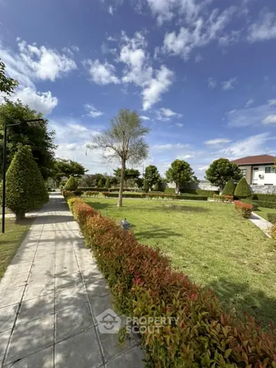 Beautiful landscaped garden with lush greenery and clear blue sky in a residential area.