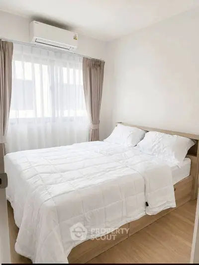 Cozy bedroom with natural light, featuring a comfortable bed and modern air conditioning unit.
