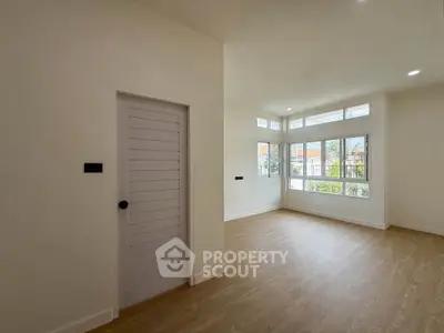 Spacious and bright room with large windows and wooden flooring, perfect for modern living.