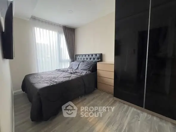 Modern bedroom with sleek black wardrobe and cozy bed in natural light.