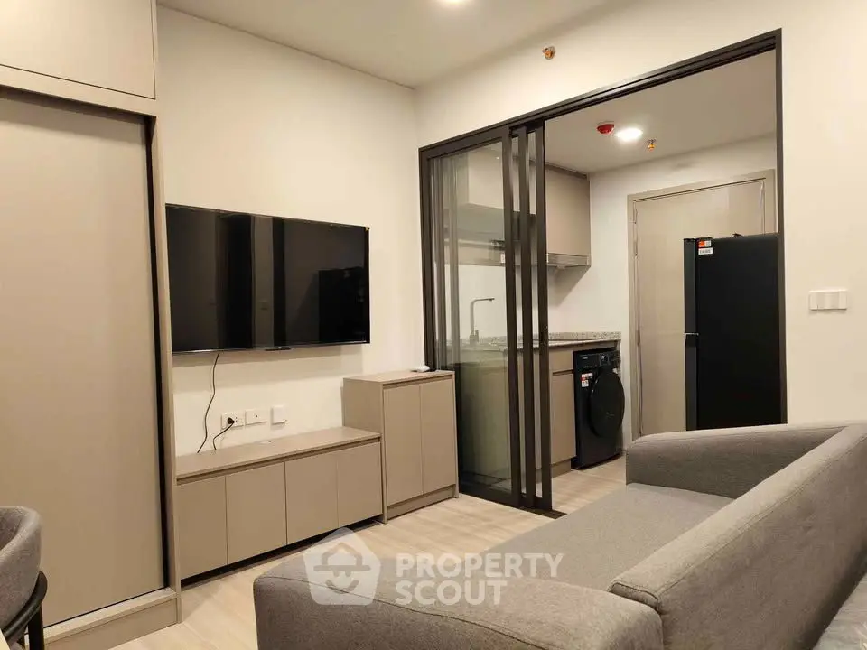 Modern living room with sleek furniture and kitchen view in a stylish apartment.
