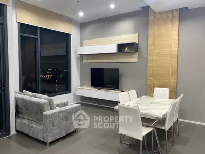Modern living room with stylish furniture and dining area, featuring large windows and elegant decor.