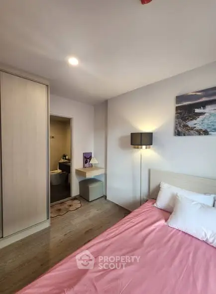 Cozy bedroom with pink bedding and modern decor, featuring a built-in wardrobe and soft lighting.