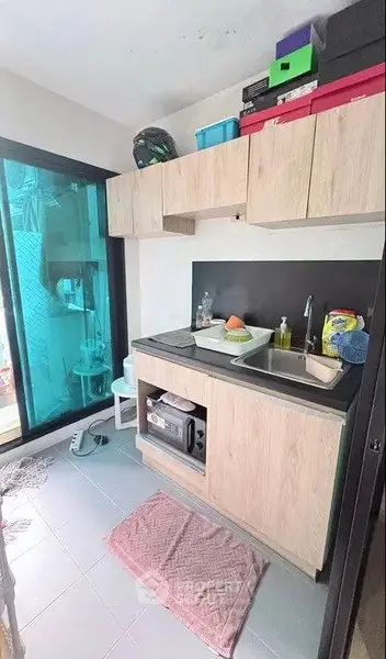 Compact kitchen with wooden cabinets and sliding glass door