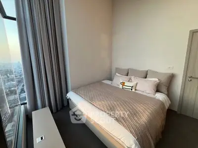 Luxurious bedroom with city view, elegant decor, and plush bedding in high-rise apartment.