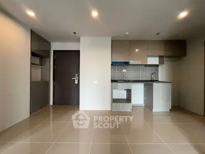 Modern kitchen with sleek cabinetry and tiled backsplash in open layout apartment.