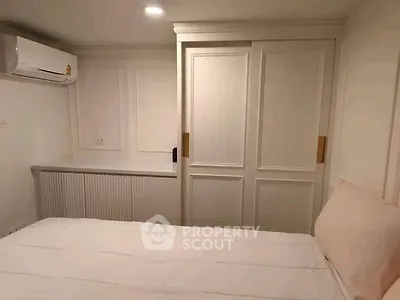Cozy bedroom with white decor and built-in storage, featuring air conditioning for comfort.