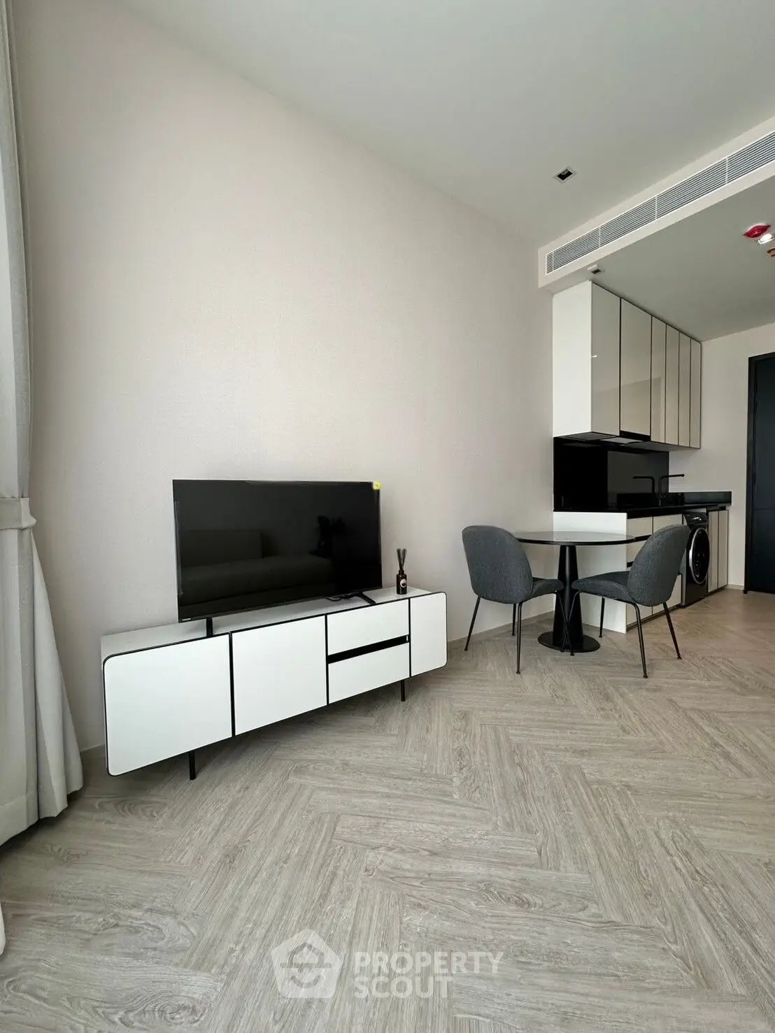 Modern living room with sleek furniture and open kitchen layout in a stylish apartment.