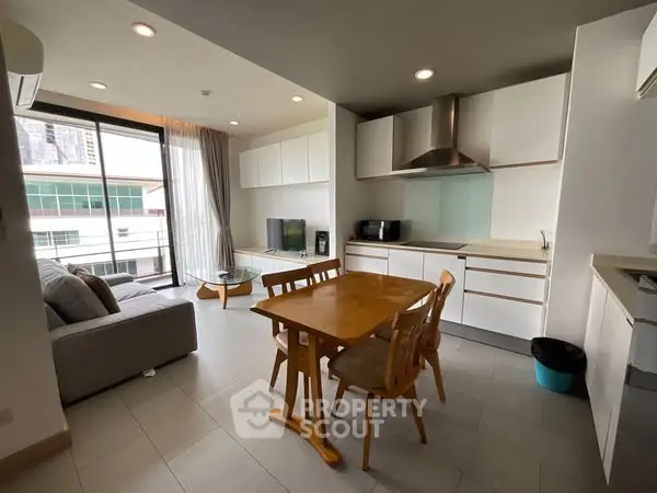 Modern open-layout living room and kitchen with city view and sleek furnishings.