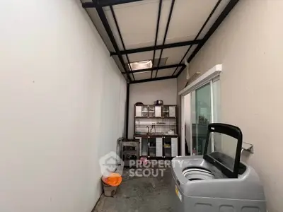 Functional utility area with washing machine and storage shelves in a modern home.