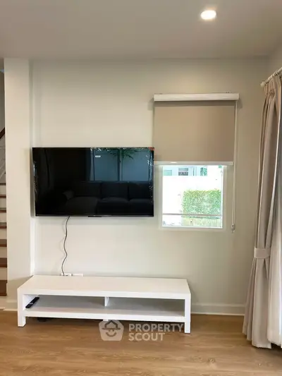 Modern living room with wall-mounted TV and sleek white console