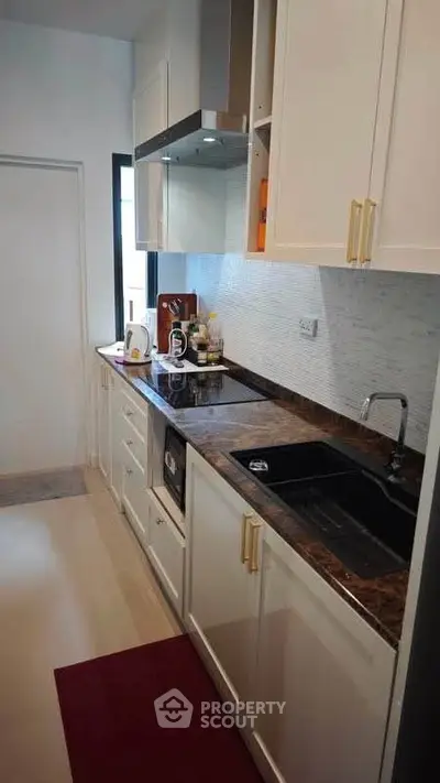 Modern kitchen with sleek cabinetry and marble countertops in a stylish apartment.