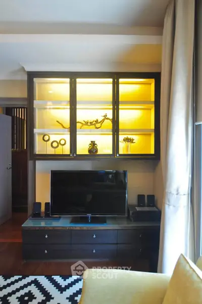 Stylish living room with modern TV setup and illuminated display cabinet