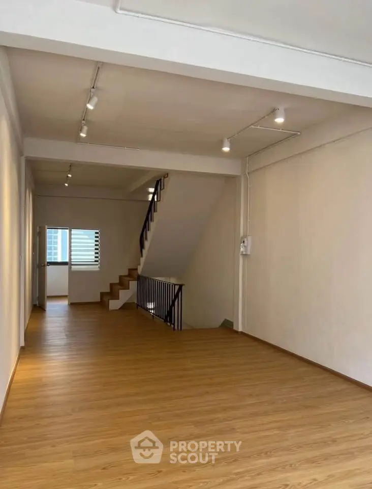 Spacious open-plan living area with wooden flooring and staircase, ideal for modern living.