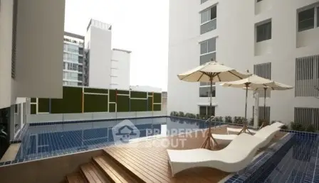 Luxurious apartment complex with modern pool and stylish sun loungers.