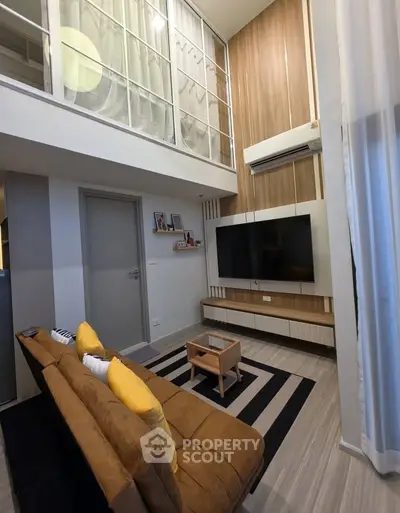 Modern living room with high ceiling, stylish decor, and cozy seating area in a contemporary apartment.