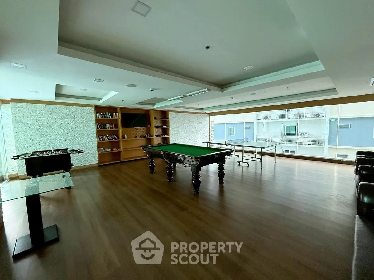 Spacious recreation room with pool table and library in modern building