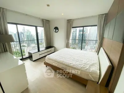 Spacious bedroom with city view and large windows in modern apartment.