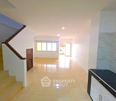 Spacious open-plan living area with tiled flooring and staircase, perfect for modern family living.