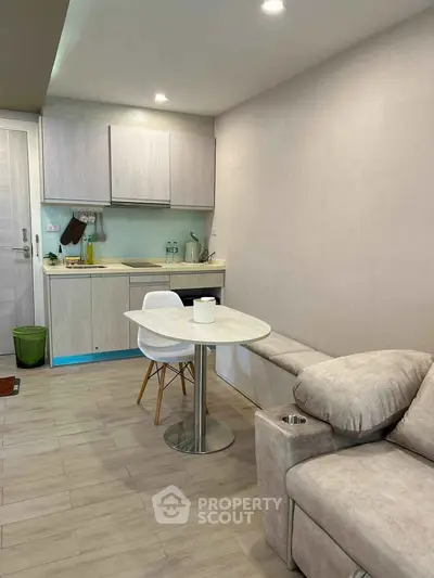Modern compact living room with integrated kitchen, featuring sleek cabinetry and cozy seating area.