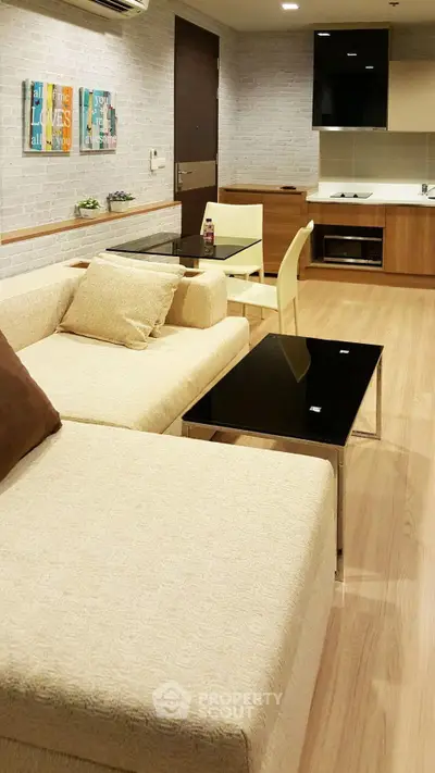 Modern living room with cozy beige sofa, sleek black tables, and stylish wall art in a contemporary apartment.