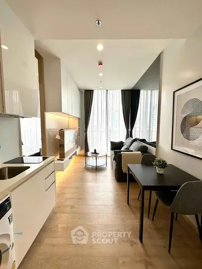 Modern living room with open kitchen, stylish decor, and large windows for natural light.