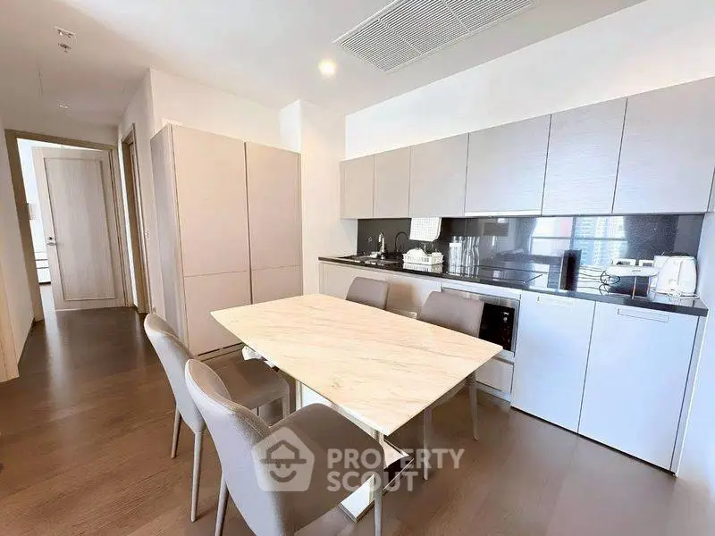 Modern kitchen with sleek cabinetry and dining area in a stylish apartment.