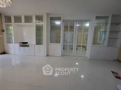 Spacious living room with elegant built-in cabinets and glossy white flooring.