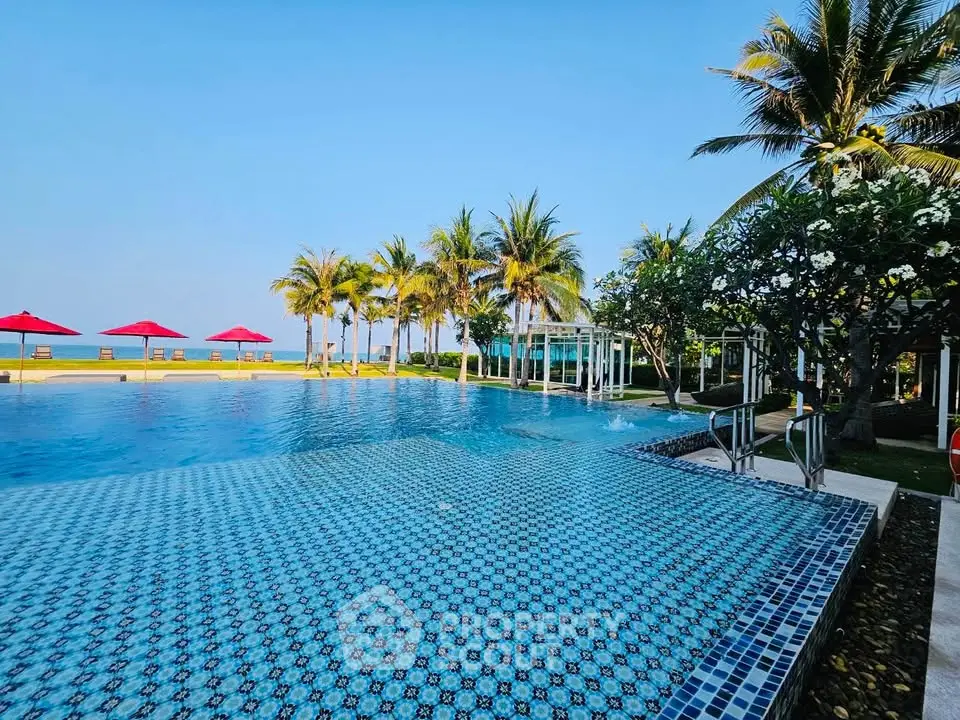 Luxurious beachfront pool with palm trees and ocean view