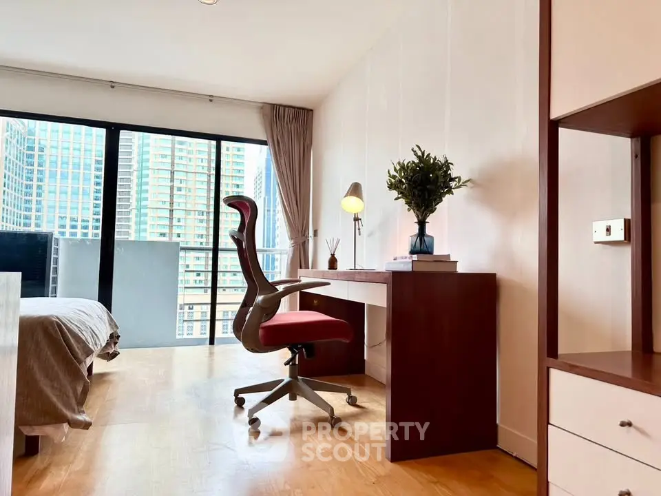 Modern bedroom with study area and city view, featuring sleek furniture and natural light.