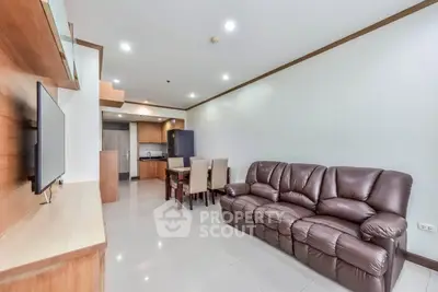 Spacious living room with leather sofa and modern dining area in open layout apartment.