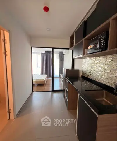 Modern apartment interior with sleek kitchen and cozy bedroom view.