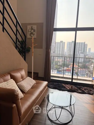 Modern living room with large windows and city view, featuring stylish sofa and glass coffee table.