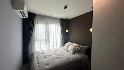 Modern bedroom with cozy bedding and natural light from large window.