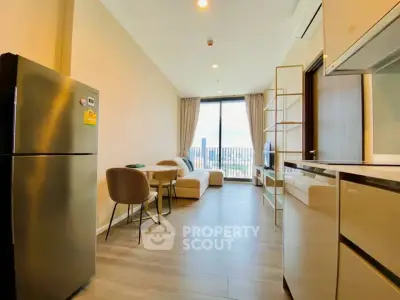 Modern living room with open kitchen and city view, featuring sleek furniture and large windows.
