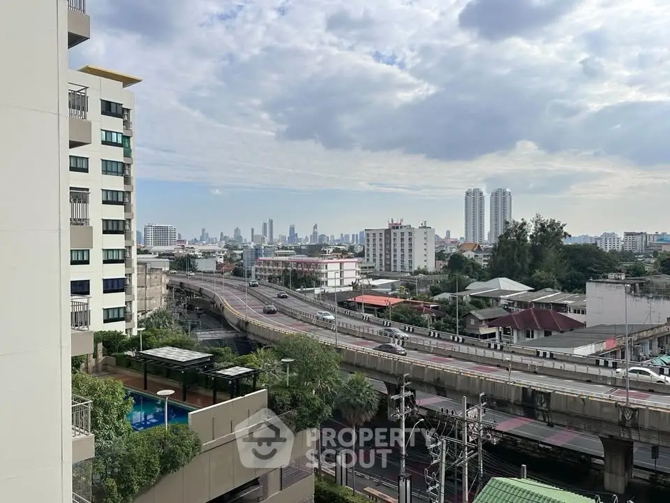 Stunning cityscape view from a high-rise building balcony, showcasing urban skyline and elevated roads.