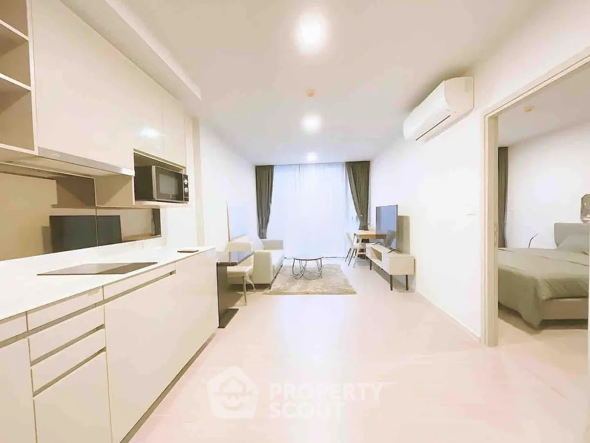 Modern open-plan living room with kitchen and bedroom, featuring sleek design and neutral tones.