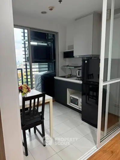 Modern kitchen with sleek black appliances and dining area in a bright apartment.