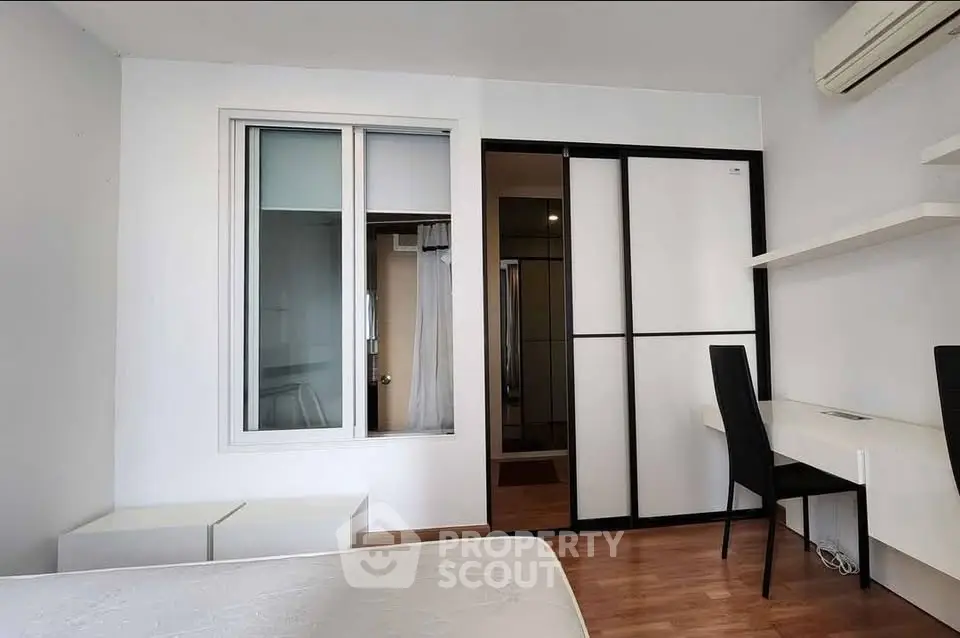 Modern bedroom with built-in wardrobe and study desk, featuring minimalist design and air conditioning.