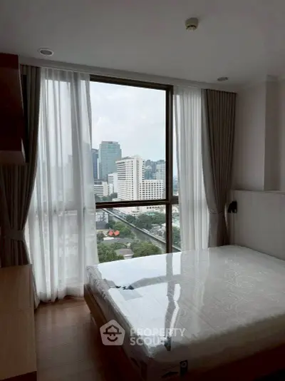 Modern bedroom with city view and large window in high-rise apartment