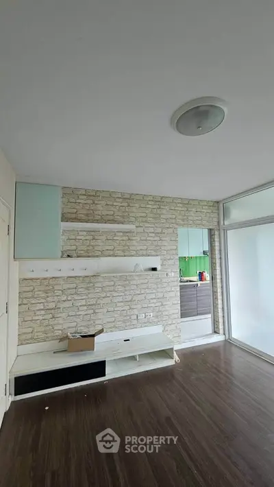 Modern living room with stylish stone accent wall and open kitchen layout.