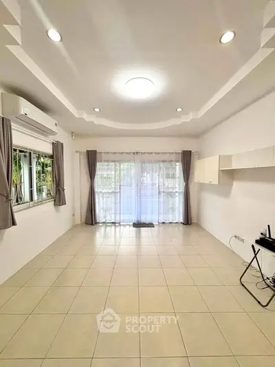 Spacious living room with modern lighting and large windows for natural light.