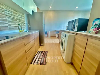 Modern kitchen with wooden cabinets and washing machine, featuring sleek appliances and stylish decor.
