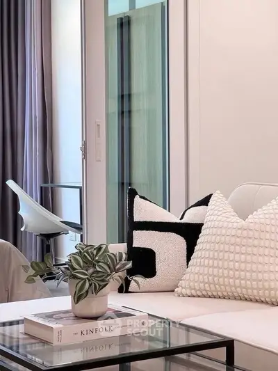 Stylish modern living room with cozy sofa, chic decor, and elegant glass coffee table.