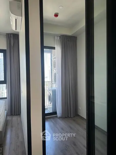 Modern bedroom with balcony access and city view, featuring sleek flooring and air conditioning.