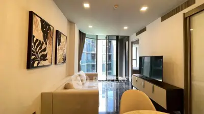 Modern living room with elegant decor and large windows offering natural light and a view of the cityscape.