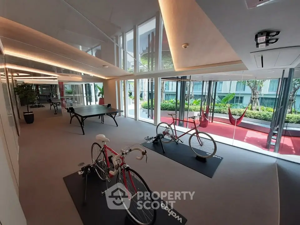 Modern building interior with cycling area and garden view, featuring sleek design and natural light.