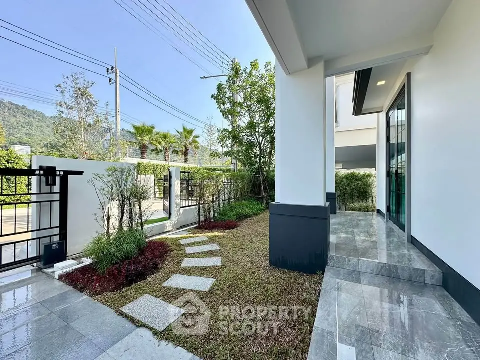 Modern home exterior with landscaped garden and stone pathway, showcasing sleek architecture and inviting entrance.