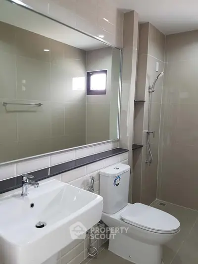 Modern bathroom with sleek fixtures and large mirror in contemporary apartment.